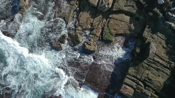 Static aerial top down waves crashing the rocks on the coast at Sydney, Australia