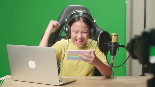 Asian Kid Girl Playing Video Game With Phone Then Celebrating While Live Stream On Green Screen
