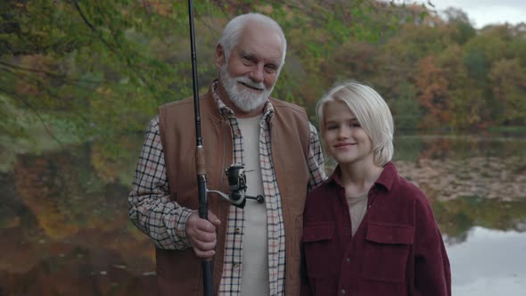 Grandpa and Grandson Standing Near Lake with Fishing Rods