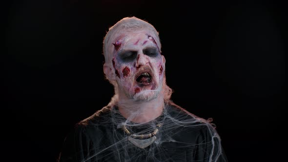 Sinister Man in Costume of Halloween Crazy Zombie with Bloody Wounded Scars Face Trying to Scare