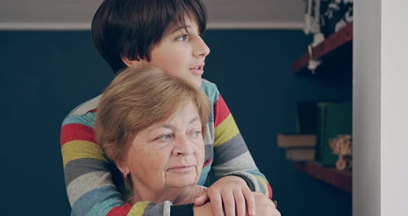 The Teenage Grandson Hugged His Grandmother Behind the Neck and Speaks to Her