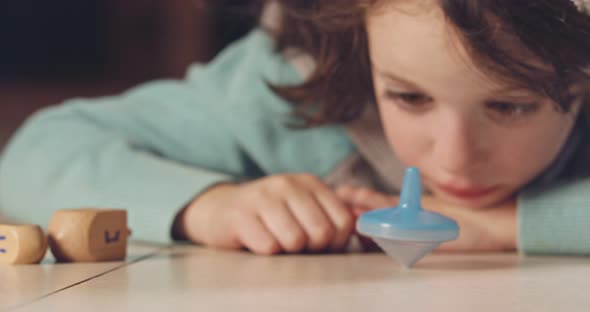 Close up shot of a girl spinning a Hanukka dreidel on the floor