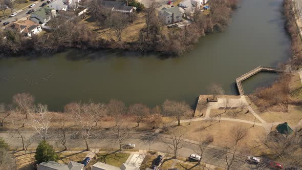 A bright and sunny morning flying over a green pond, shot with a drone. The camera, while tilted dow