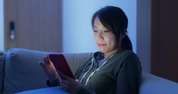 Woman use of smart phone sit on sofa at home in evening