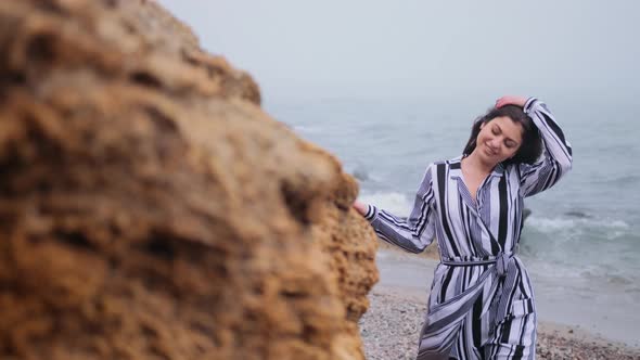 Beautiful Young Woman Stands at Rock Resting