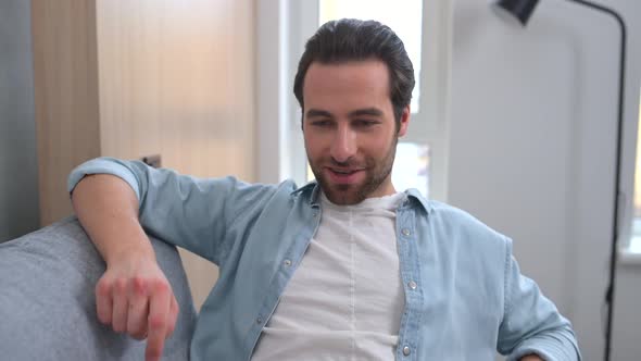 Optimistic Man in Casual Wear Using Laptop While Sitting on the Couch