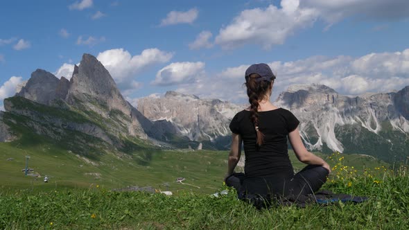 Woman sitting on the grass admiring Dolomites mountains, Italy