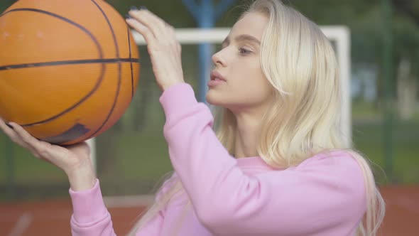 Close-up Portrait of Young Beautiful Woman Spinning Sports Ball Outdoors and Looking at Camera