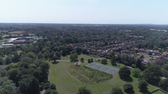 Aerial shot on a sunny day over a park and tennis courts in Solihull, Birmingham, UK