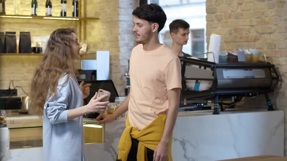 Young Positive Man and Woman Standing and Talking Waiting for Coffee in Cafe