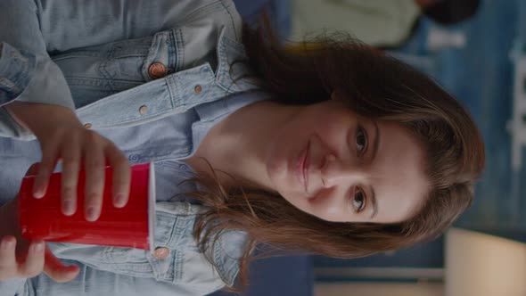 Vertical Video Portrait of Woman Sitting on Sofa Similing at Camera While Drinking Beer