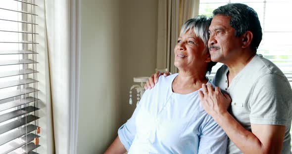 Senior couple looking through window 4k