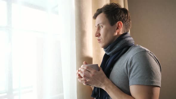 Sick Man with Hot Drink Near Window