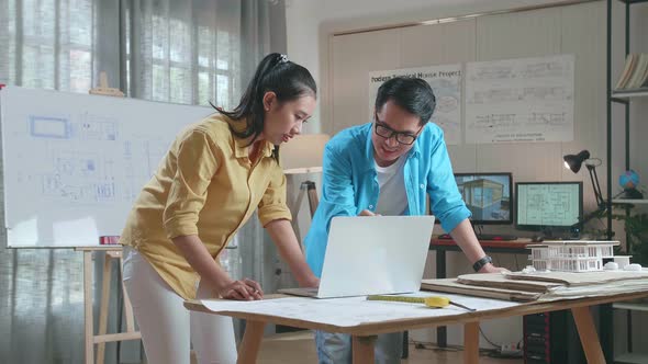 Asian Woman And Man Engineers With Laptop Computer Discuss About Design At The Office