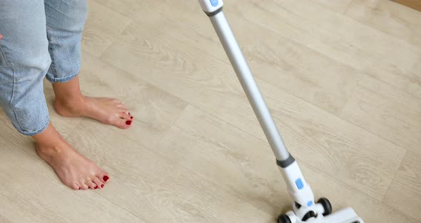 Unrecognizable female using modern vacuum cleaner to remove dust from floor