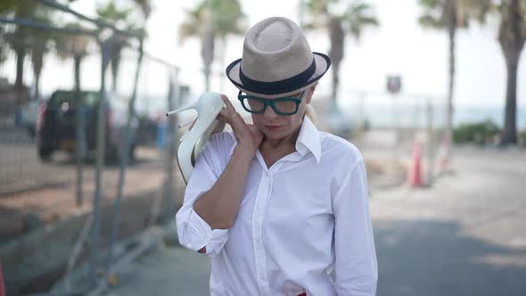 Portrait of Overworked Beautiful Businesswoman Strolling with Highheels on Shoulder and Leaving