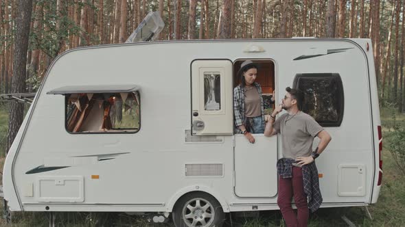 Happy Couple with Camper Talking in Forest