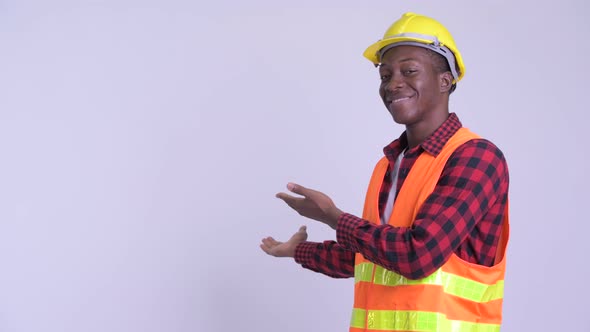 Young Happy African Man Construction Worker Showing Something To the Back