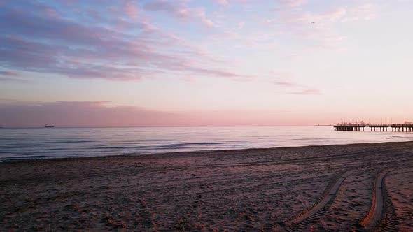 Walking out on a beach during sunrise. Orange and purple colors. Empty beach. Turning right towards