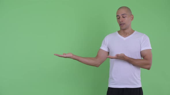 Stressed Bald Man Showing Something and Giving Thumbs Down