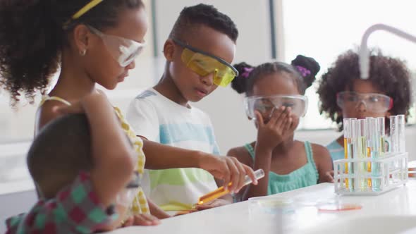 Video of happy african american pupils doing experiment during chemistry lesson