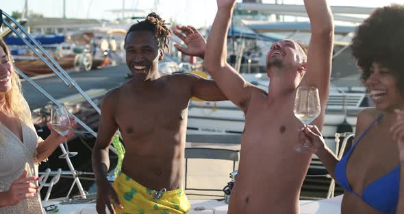 Happy multiracial friends having fun dancing and drinking champagne at boat party outdoor