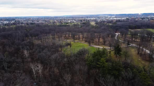 Aerial over forest park in late fall. City in background