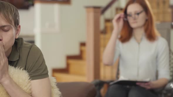 Depressed Young Man in the Office of Psychologist, Holding Fluffy Pillow in the Foreground