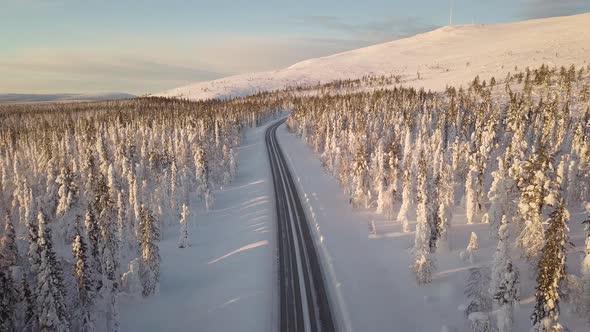 Cars driving on a empty road surrounded by snowy trees in Lapland Finland.