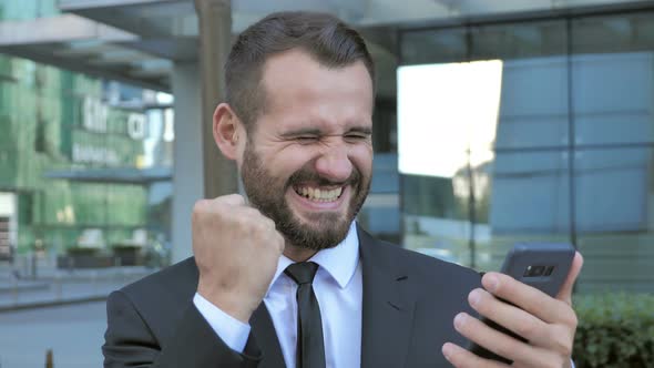 Beard Man Excited for Success while Using Smartphone