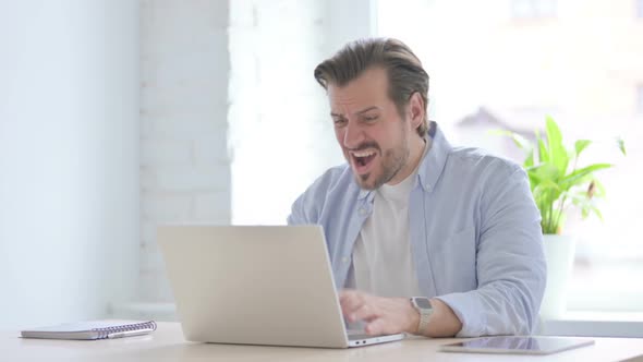 Young Man Reacting to Loss While Using Laptop