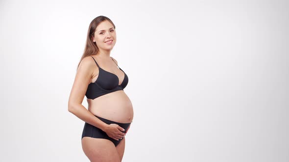 Young, happy and healthy pregnant woman in front of white background.