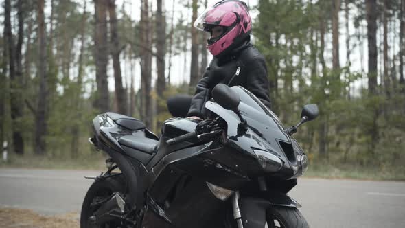 Confident Young Woman Approaching Motorbike, Sitting on It, and Closing Helmet Visor. Portrait of