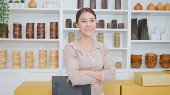 Portrait of Asian business woman work to check vase goods order for customer from shelf at store.