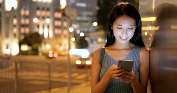 Business woman using smart phone in the city at night 