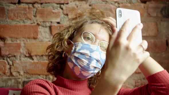Portrait of a Modern Woman in Glasses and a Protective Mask with the Image of the Sky Takes a Selfie