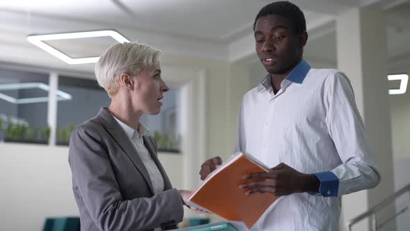 Dissatisfied Female CEO Talking with Inefficient Male Employee Standing in Office Lobby Indoors