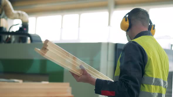 Factory Employee in a Face Mask Is Observing a Piece of Wood