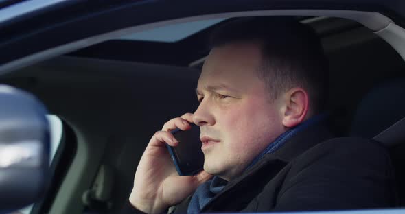 Businessman Sitting Behind The Wheel Talking On A Mobile Phone