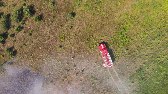 A Fire Engine Shrouded in Smoke From a Fire in a Field