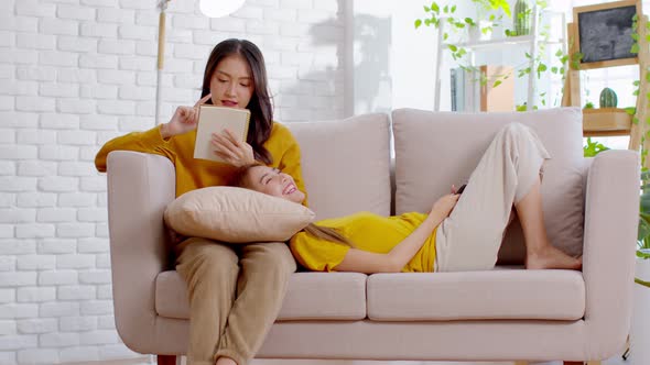 Asian lesbian couple so happy with girlfriend lie on a partner's lap on the couch