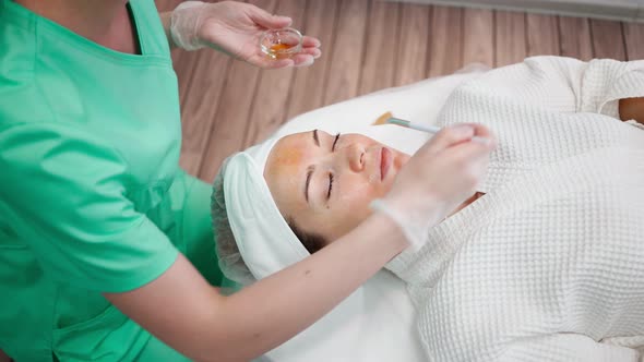 Girl Beautician Makes Facial Cleansing Procedure for Young Woman in Beauty Salon