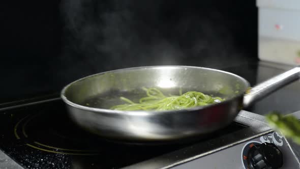A Chef In The Kitchen Cooking A Green Spaghetti Pasta On The Electric Stove.-closeup shot