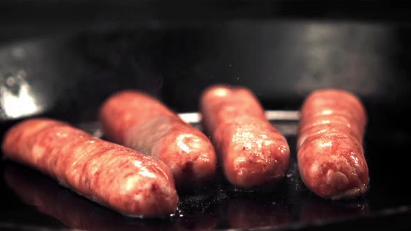 Super Slow Motion Raw Sausages are Fried in Oil in a Frying Pan with Hot Steam