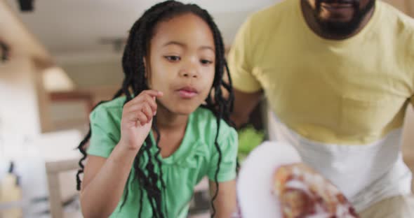 Happy african american father and daughter doing science experiments with artificial volcano