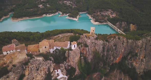 Aerial drone cinematic 4K footage of a battlement and a village on top of a rock where a large reser