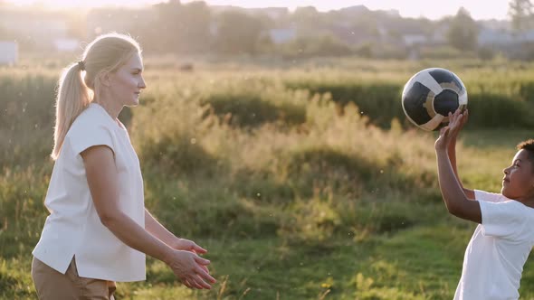 Mother and Son Are Playing with a Ball in a Summer Field