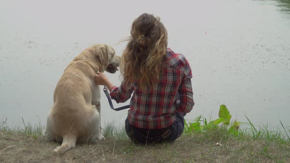 Curly Woman and Labrador Is Sitting Near the River