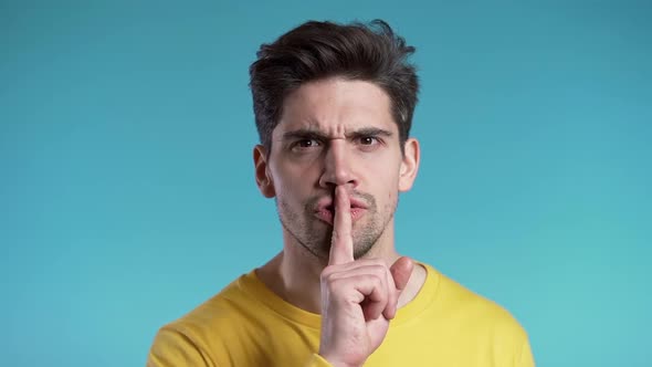 European handsome man holding finger on his lips over blue background. Gesture of shhh