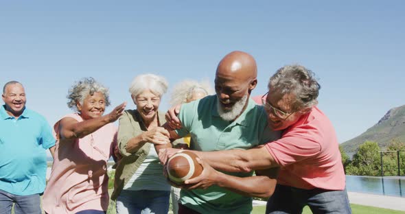 Happy senior diverse people playing rugby in garden at retirement home